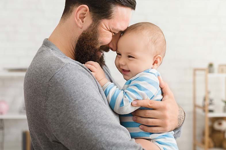 a father holding his baby to his chest as they both smile